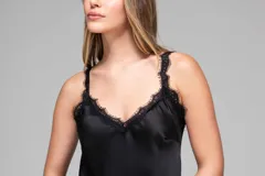 Vestido largo de seda color rojo, con escote en V y breteles finos. Presenta detalles de encaje en el escote y un diseño asimétrico en la falda que incorpora encaje transparente desde la altura de la rodilla.