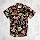 Camisa de hombre de manga corta con estampado floral multicolor sobre fondo negro.