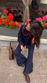 Camisa de jean oscuro con cuello redondo y ribetes rojos, manga larga y cierre frontal con botones.