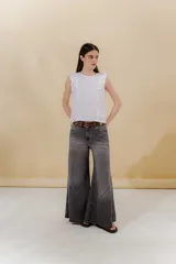 Jean de tiro medio color gris oscuro, con cortes curvos en el ruedo que generan un movimiento elegante. Tiene un ajuste en la cintura y es súper amplio en las piernas. Incluye bolsillos delanteros y plaque en la espalda.