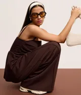 Top marrón oscuro con escote recto y breteles finos. Presenta un efecto drapeado en el torso y un peplum con volados en el bajo.