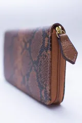Billetera rectangular con cierre perimetral, confeccionada en cuero con textura de reptil. Cuenta con múltiples compartimentos internos para tarjetas, documentos y billetes, además de un bolsillo interior con cierre para monedas.