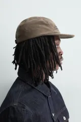 Gorra de cinco paneles confeccionada en pana de algodón, con visor plano y ajuste posterior. Presenta un bordado frontal con el texto 'Lassen Field'.