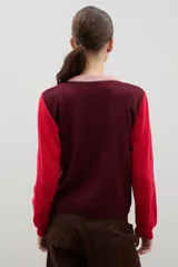 Saco de punto con diseño color block, presenta cuerpo en color bordó, mangas en color rojo y tapeta frontal con cuello redondo en color rosado. Posee cierre frontal con botones y puños acanalados.