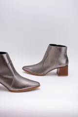 Botas cortas de cuero color beige, con punta fina y cierre lateral. Tienen un taco cuadrado de madera.