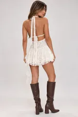Vestido corto negro de encaje con diseño halter, escote en V profundo, falda con volados y short integrado.