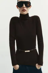 Jersey de punto liso confeccionado en 100% lana, con cuello subido y manga larga. Incluye un cinturón fino integrado a la altura de la cintura.