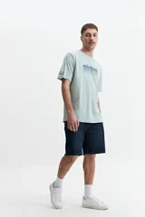 Remera básica de algodón color gris claro, con cuello redondo y logo estampado en el pecho en tonos verdes.