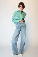 Jeans de tiro alto con corte wide leg y pernera ancha. Presenta bolsillos de plastrón en el delantero y cierre frontal con cremallera y botón.