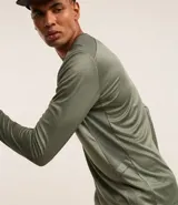 Remera deportiva de manga larga con cuello redondo, confeccionada en tejido técnico Dry Fit. Presenta un diseño liso en color negro con detalles reflectantes en los hombros.