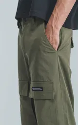 Pantalón cargo de color verde militar, corte recto y holgado, con bolsillos cargo a la altura de los muslos y detalles de costuras reforzadas en las rodillas.