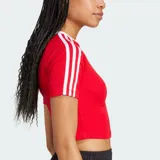 Remera corta roja ajustada al cuerpo, de manga corta, con cuello redondo blanco y las icónicas tres líneas blancas de Adidas en las mangas. Cuenta con el logo del trifolio bordado en el pecho.