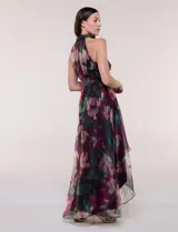 Vestido largo sin mangas de la marca RM Richards, con cuello alto halter y diseño asimétrico. Presenta un estampado floral en tonos bordó, verde y rosado sobre base satinada, con lazo ajustable en la cintura y falda fluida con capas asimétricas.