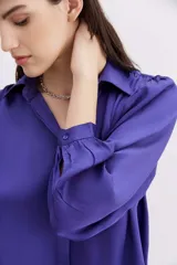 Camisa fluida de manga larga, color negro, con cuello camisero, puño con botón y detalle de frunces.