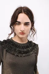 Remera de manga larga confeccionada en tejido de lurex negro con destellos dorados. Detalle de volados en el cuello tipo collar.