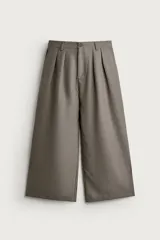 Pantalón relaxed fit de color gris, confeccionado con tejido que incluye lino, con pliegues frontales en la cintura, bolsillos delanteros y cierre frontal con cremallera y botón.