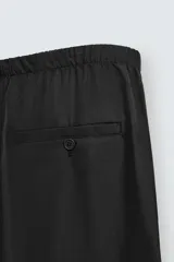 Pantalón de corte relajado confeccionado en tejido fluido con mezcla de lyocell. Presenta cintura elástica ajustable con cordón, bolsillos laterales y un bolsillo trasero de vivo con botón.
