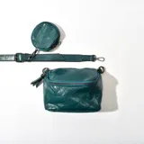 Bandolera azul con diseño acolchado de rombos, correa ajustable y monedero circular colgante.