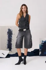 Bermuda cargo de denim color gris con efecto lavado, de tiro medio y corte amplio. Presenta bolsillos laterales tipo cargo con solapa, bolsillos delanteros clásicos y cierre frontal con botón y cremallera.