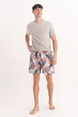 Short de baño para hombre con estampado de hojas tropicales en tonos rosa oscuro, verde azulado y blanco. Presenta cintura elástica con cordón de ajuste blanco.
