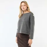 Sweater de punto color gris, de corte recto y largo a la cintura. Presenta cuello redondo y detalle de botones decorativos dorados en uno de los hombros.