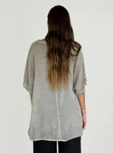 Blusa blanca de lino y algodón con cuello redondo y mangas cortas. Diseño holgado con ruedo irregular y detalle de volados.