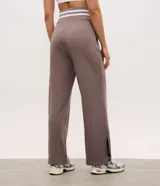 Pantalón deportivo de corte recto color marrón, confeccionado en una mezcla de modal y algodón. Presenta cintura elástica en rib con rayas blancas contrastantes, bolsillos laterales y detalle de lettering bordado en la pierna. Incluye aberturas laterales en el ruedo.