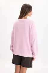 Buzo rosa de corte holgado y diseño liso, con cuello redondo, mangas largas y puños ajustados.