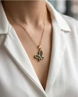 Dije de acero con baño de oro en forma de mariposa con relleno negro.