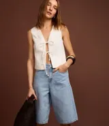 Bermuda tipo jorts de tiro alto confeccionada en denim de algodón, con diseño de cinco bolsillos, trabillas para cinturón y cierre frontal con botón y cremallera.