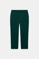 Pantalón de tiro alto color beige, de corte recto y largo tobillero, con bolsillos laterales y cierre frontal con cremallera y ganchos metálicos.