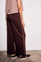 Pantalón deportivo de corte recto y holgado, confeccionado en algodón color marrón chocolate. Presenta una cintura elástica con cordón ajustable y una franja lateral decorativa en tono más claro.