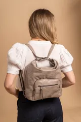 Cartera mochila color tostado, de cuero sintético, con compartimento principal amplio y bolsillos frontales con cierre. Tiene correas ajustables y asa superior para llevar al hombro o como mochila.