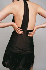 Vestido corto de cuello halter con espalda descubierta, diseño con frunces en el cuerpo y bajo con lentejuelas brillantes. Cuenta con forro interior y cierre trasero con cremallera oculta.