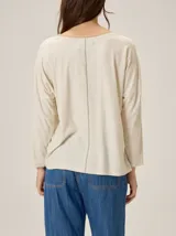 Remera de silueta relajada con diseño de paneles en tonos beige y crema, cuello redondo y mangas tres cuartos.