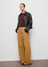 Jeans de tiro bajo y diseño wide leg, confeccionados en tejido de pana color tostado, con cinco bolsillos, trabillas para cinto y cierre frontal con botón y cremallera.