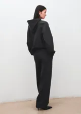 Hoodie de corte oversize color gris oscuro, con capucha ajustable, bolsillo estilo canguro en el frente, mangas largas y puños y ruedo elásticos acanalados.