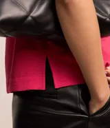 Blusa fucsia de manga corta con cuello redondo pespunteado, diseño sin estampa y efecto airflow con textura sutil. Cuenta con abertura trasera tipo gota y cierre con botón.