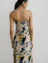 Vestido midi de tirantes finos con estampado floral en tonos azul, negro y naranja. Tiene escote redondo y tajo lateral.