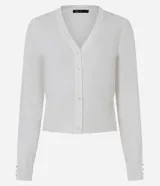 Cardigan blanco de punto con cuello en V, cierre frontal con botones perlados y mangas largas. Las mangas tienen un ligero fruncido en los hombros y los puños tienen tres botones perlados decorativos.