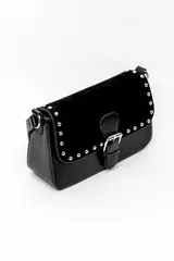 Bolso negro confeccionado en poliuretano y gamuza, con solapa decorada con tachas plateadas y cierre frontal de hebilla metálica.
