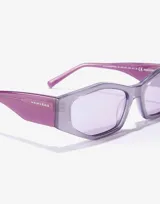 Lentes de sol Hawkers modelo Aperol con armazón de diseño geométrico en color gris con acabado brillante y patillas en tono violeta traslúcido. Cuentan con cristales en tono lila claro.
