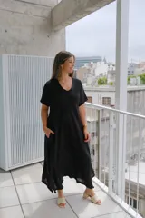 Vestido largo negro de manga corta, con corte acampanado y bajo asimétrico con detalle deshilachado en picos desiguales.