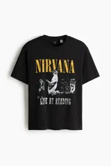 Remera de algodón color negro con cuello redondo y mangas cortas. Presenta un estampado frontal con el logo de la banda Nirvana en color amarillo y una imagen en blanco y negro del concierto Live at Reading.