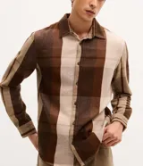 Camisa de franela a cuadros en tonos marrones y beige, con cuello camisero, cierre frontal de botones y manga larga. De corte regular.