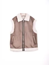 Chaleco color marrón con forro de piel sintética blanca en el cuello, sisas y dobladillo. Tiene cierre frontal de cremallera y dos bolsillos laterales.