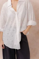 Camisa lila oversize de algodón con bordado floral calado tipo broderie, cuello camisero, manga larga y abotonadura frontal.