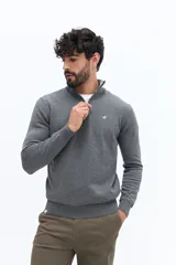 Sweater de tejido liso color verde oscuro, con cuello medio y cierre frontal parcial plateado. Presenta puños y cintura acanalados, y un pequeño logo bordado en el pecho.