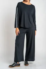 Pantalón de corte wide leg color negro, confeccionado en tejido de algodón con elastano. Presenta una franja lateral blanca a lo largo de cada pierna y cintura elástica.