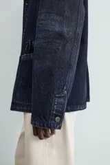 Cazadora de denim de algodón azul marino oscuro, corte regular fit, con cuello solapa, bolsillos frontales de plastrón y cierre de botonadura frontal.